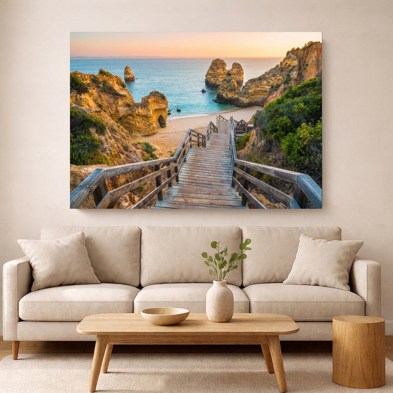 Beach scene with wooden walkway and cliffs on a wall above a beige sofa.
