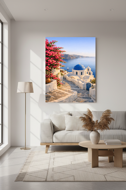 Large Santorini photograph showing whitewashed buildings, blue domes, stone steps, and bright pink bougainvillea overlooking the sea, displayed above a light gray sofa in a modern minimalist living room.