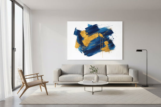 Large abstract painting with bold blue and gold brushstrokes on a pure white background, displayed above a light gray sofa in a modern minimalist living room.
