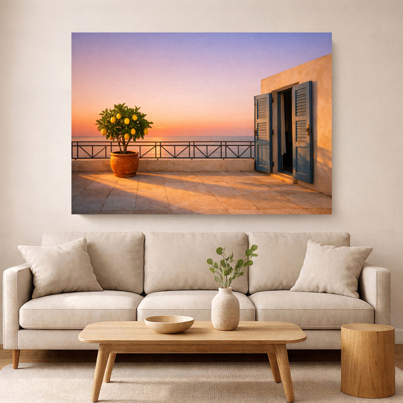 A large rectangular wall art print showing a sunset terrace with a lemon tree and an open doorway, displayed above a light beige sofa in a modern living room.