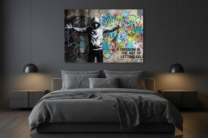 Freedom Is the Art of Letting Go Banksy-style graffiti canvas wall art with hooded figure breaking chains displayed above a bed in a moody modern bedroom - Portugal Canvas Co