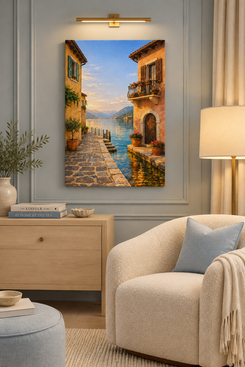 Vertical lakeside village canvas beside a cream chair in a powder blue reading nook lit by lamps - Portugal Canvas Co