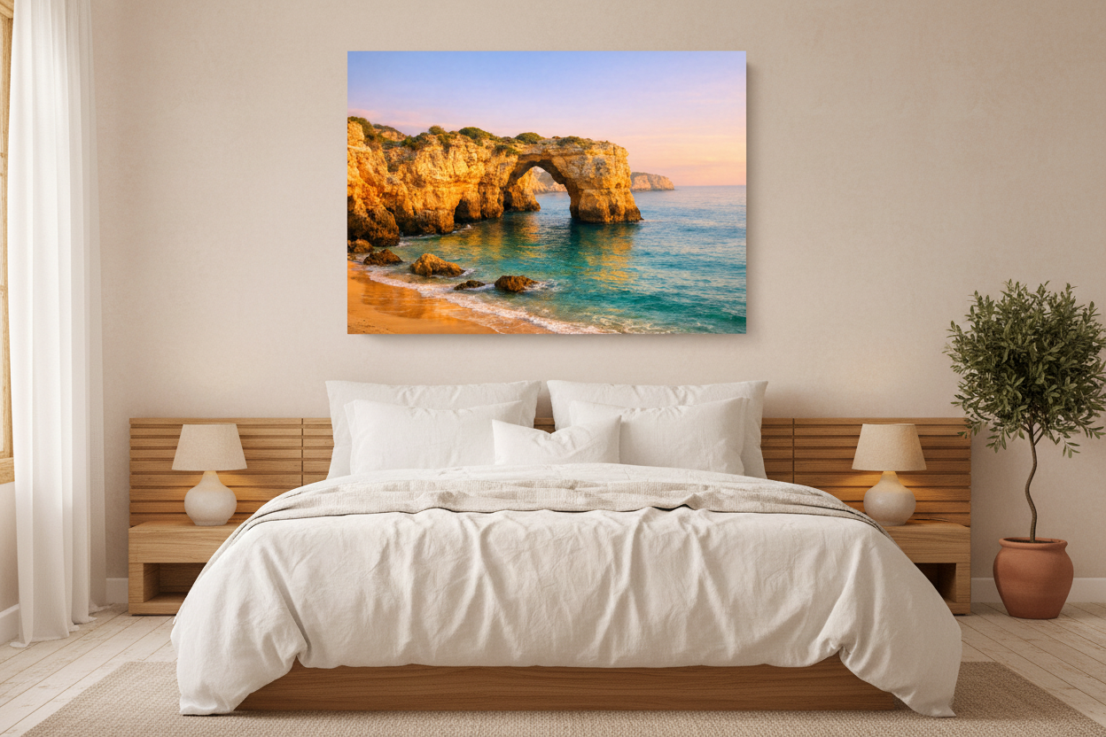 Praia da Marinha Algarve golden limestone stone arch over turquoise water canvas wall art displayed above a bed in a warm Mediterranean-style bedroom - Portugal Canvas Co