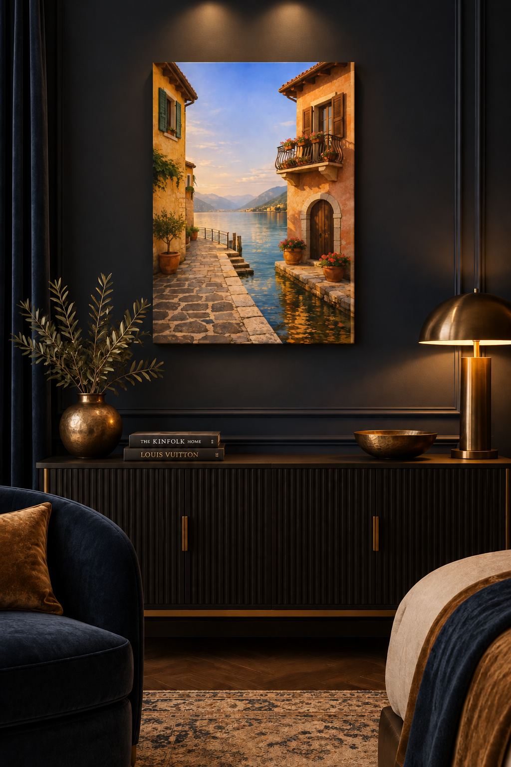Vertical lakeside village canvas above a console in a navy and bronze room lit by lamps - Portugal Canvas Co