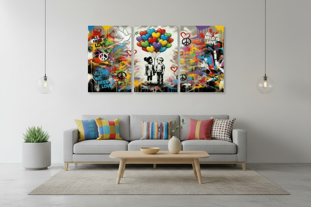 All We Need Is Love graffiti triptych canvas wall art displayed above a grey sofa in a contemporary urban living room with colourful cushions - Portugal Canvas Co