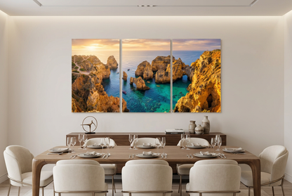 Three-panel coastal sunset canvas showing golden cliffs and turquoise sea in an elegant dining room - Portugal Canvas Co