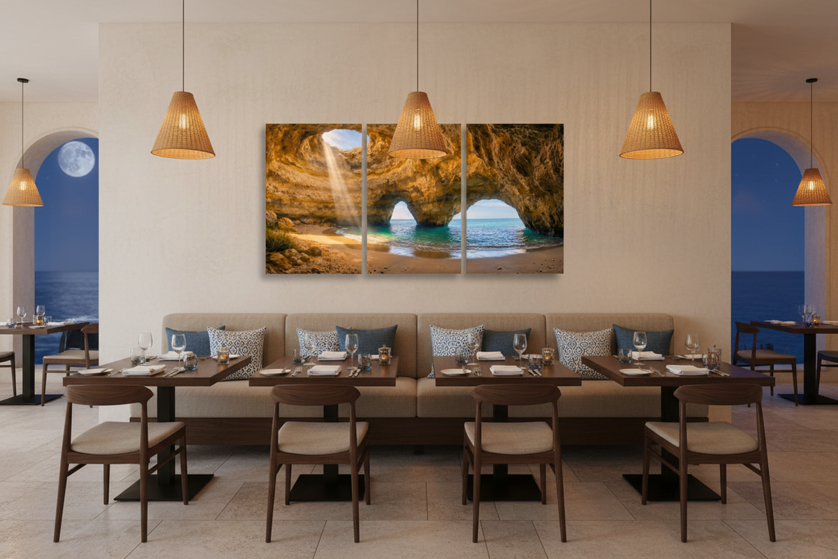 Benagil cave triptych canvas wall art above banquette seating in upscale coastal restaurant with dark wood tables and warm pendant lighting - Portugal Canvas Co