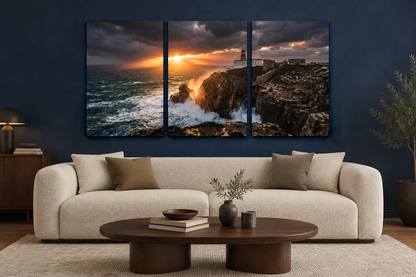 Lighthouse storm sunset three-panel canvas above a cream sofa in a navy living room - Portugal Canvas Co