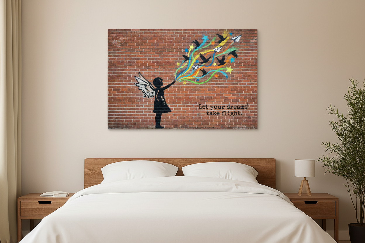 Let Your Dreams Take Flight Banksy-style graffiti canvas wall art with winged girl silhouette releasing colourful birds and paper planes displayed above a bed in a bright modern bedroom - Portugal Canvas Co