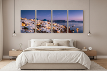 Santorini at night four-panel canvas wall art displayed above a king bed with white linen in a luxury bedroom interior - Portugal Canvas Co