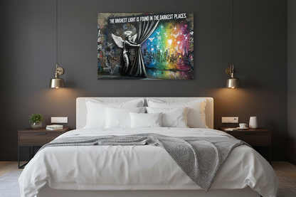 The Brightest Light Is Found in the Darkest Places Banksy-style graffiti canvas wall art with angel, rainbow cityscape and doves displayed above a bed in a moody dark bedroom - Portugal Canvas Co