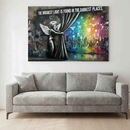 The Brightest Light Is Found in the Darkest Places Banksy-style graffiti canvas wall art with angel, rainbow cityscape and doves displayed above a sofa in a bright modern living room - Portugal Canvas Co


