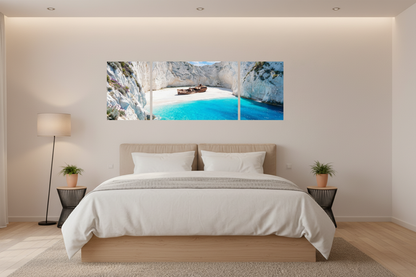 Navagio Shipwreck Beach 3-panel triptych canvas wall art displayed above a bed headboard in a minimalist Scandinavian bedroom with white linen, oak floors and bedside plants - Portugal Canvas Co
